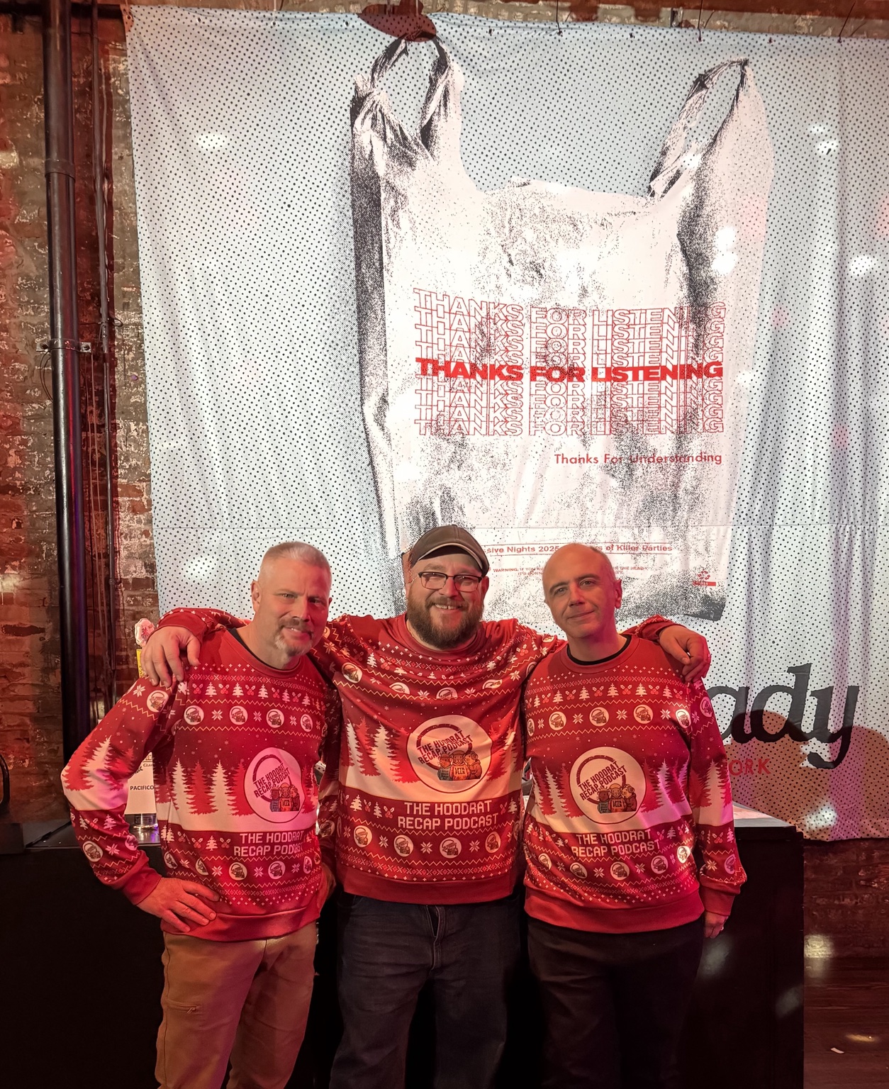The three Hoodrat Recap hosts together in matching red podcast sweaters