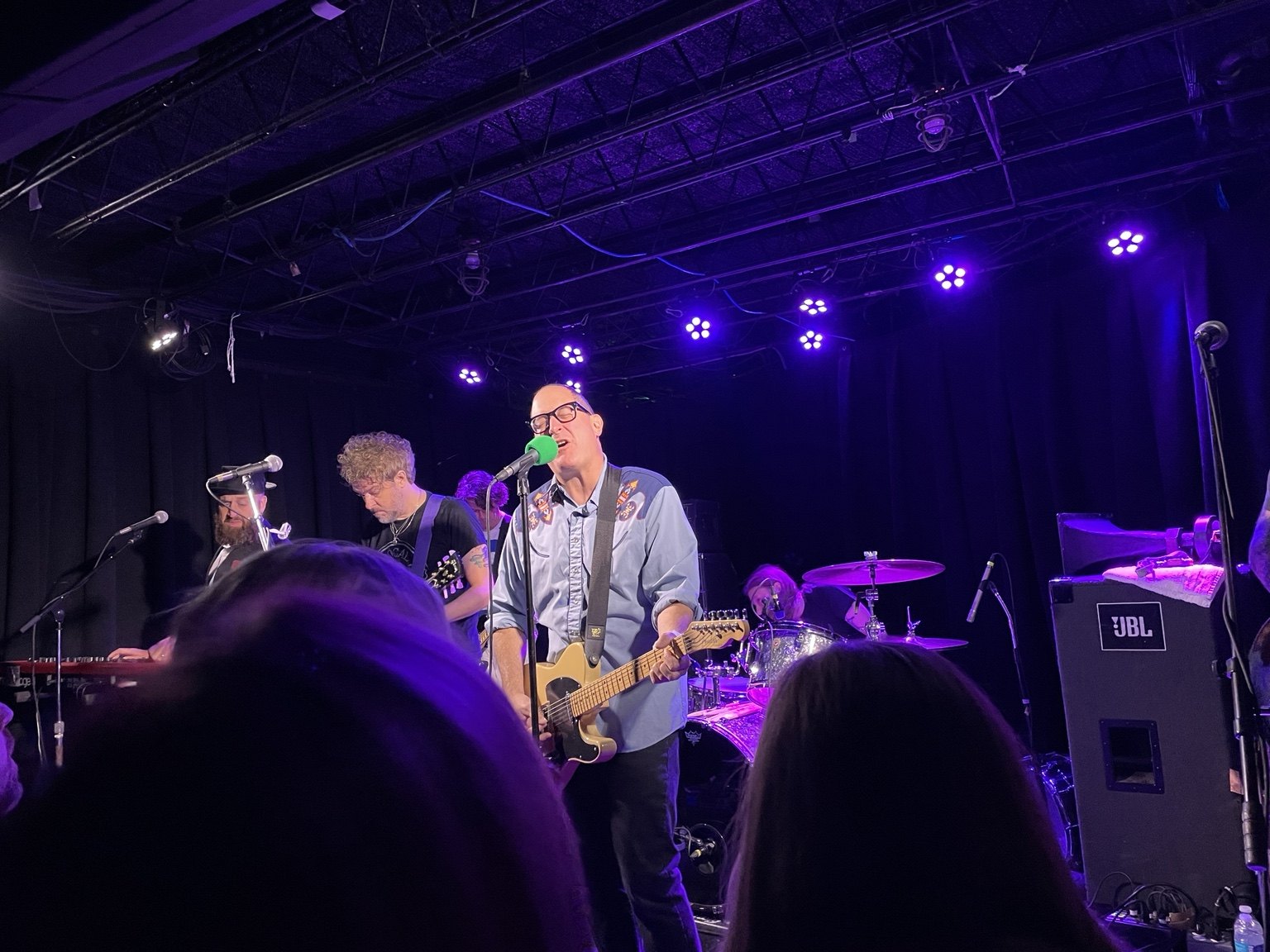 A musician performing under purple lights on stage